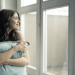 Beautiful woman smiling while looking outside the window